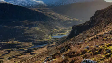Spectacular mountain view with a clear blue sky, rocky terrain, and distant snow-capped peaks, ideal for nature lovers.