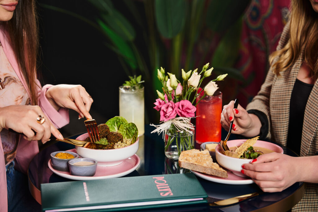 Enjoy gourmet dining with fresh salads and cocktails at our luxury hotel, surrounded by elegant floral arrangements.