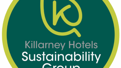 A circular logo with a green border, featuring a leaf outline forming the letter 