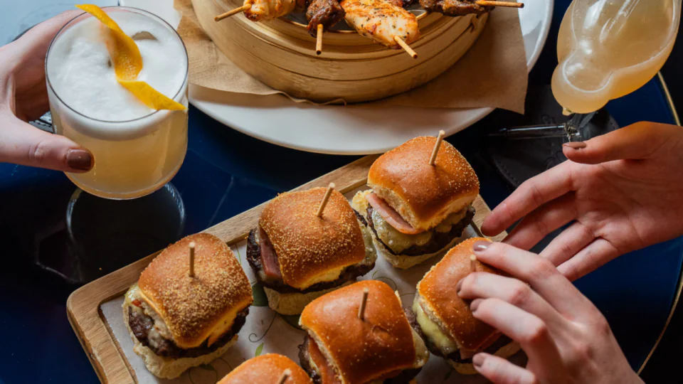 Guests enjoy gourmet sliders and cocktails at the hotel lounge, a vibrant setting ideal for socialising and relaxation.