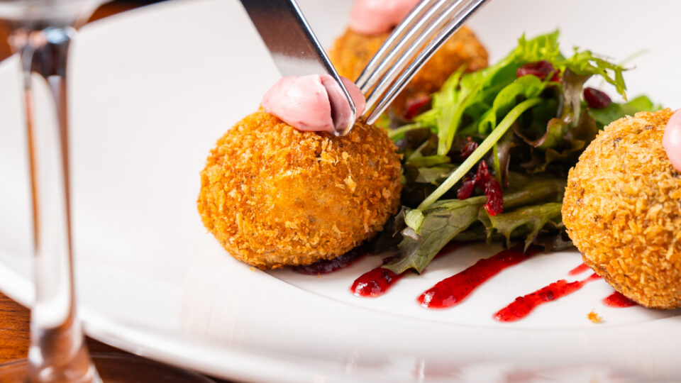 Enjoy gourmet dining with crispy croquettes, fresh greens, and rich red wine at our luxurious hotel restaurant.